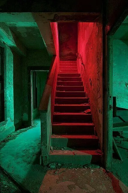 Reference photo — abandoned staircase washed in red against green-lit walls